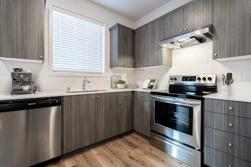 Vancouver, WA, Apartments Near Walnut Grove Park - Minnehaha Meadows - Kitchen with Vinyl Plank Flooring, Wood Cabinetry, Windows with Blinds, and Stainless Steel Appliances.