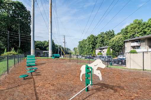 Fenced dog park with agility equipment and trees at Mirador at Peachtree, pet-friendly apartments in Atlanta.