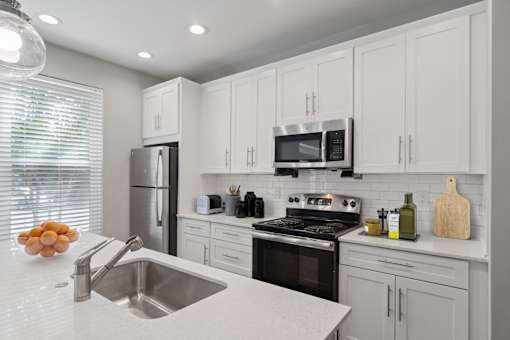 Modern kitchen with stainless steel appliances and white cabinets inside Mirador at Peachtree apartments in Atlanta, GA.
