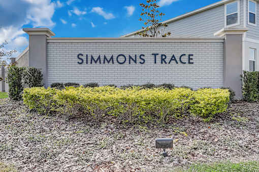 A sign that says "SIMMONS TRACE" in front of a building.
