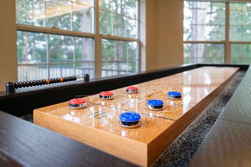 A shuffleboard table with blue and red pucks.