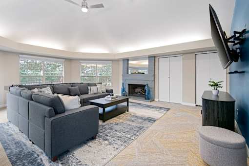 A living room with a grey couch, a coffee table, a television, and a fireplace.
