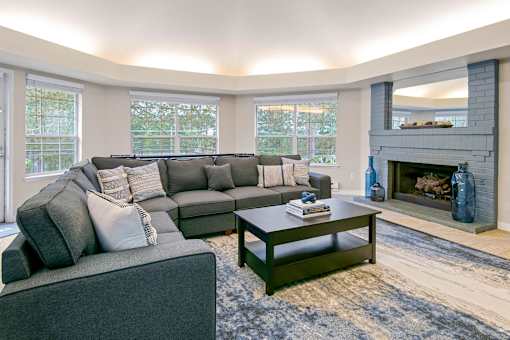A grey couch with pillows sits in a living room with a fireplace.