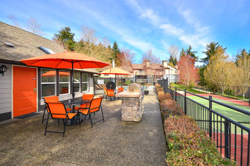 Apartments for Rent Bothell WA - North Creek Heights - BBQ Area near Pool with Grilling Station, Tables, Chairs, and Umbrellas