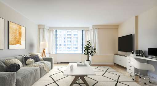 A modern living room with a grey sofa, a coffee table, a television, and a desk with a computer.