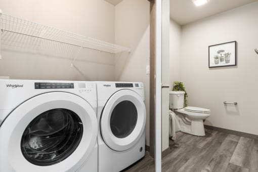 a bathroom with a washer and dryer and a toilet,