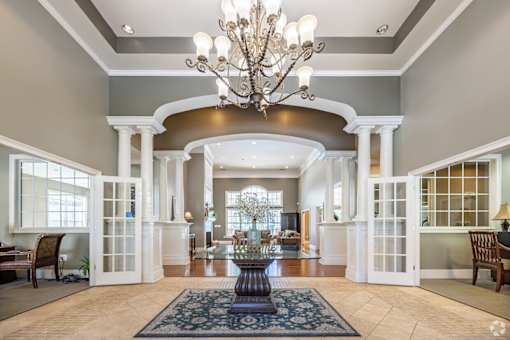 A large foyer with a chandelier, a fountain, and a rug.