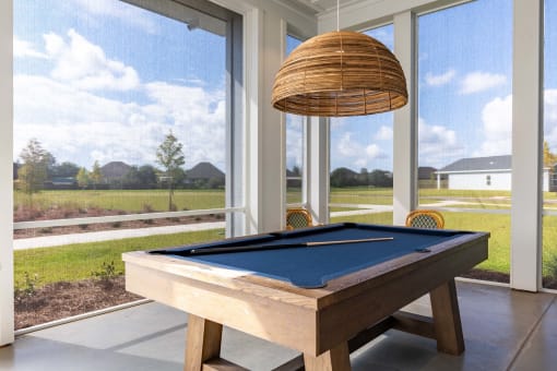 a pool table in a screened in porch with a lamp