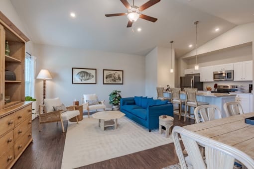 a living room with a blue couch and a kitchen with a table and chairs