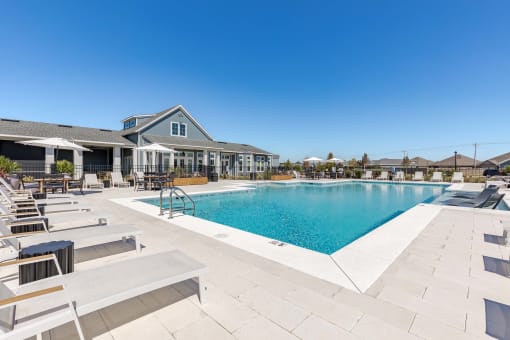 a swimming pool with lounge chairs and a building in the background