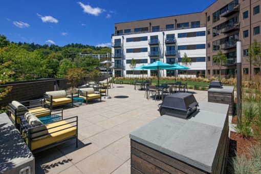 Apartments South Portland - Oxbow49 - Expansive Courtyard with Various Lounge Seating and Grill Stations Surrounded by Lush Landscaping