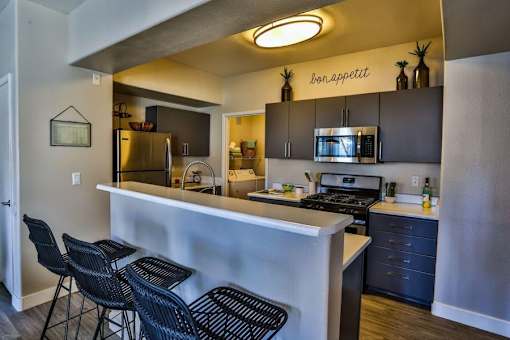 A kitchen with a bar area and chairs.
