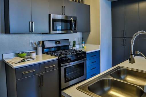 A modern kitchen with a stove, microwave, and sink.