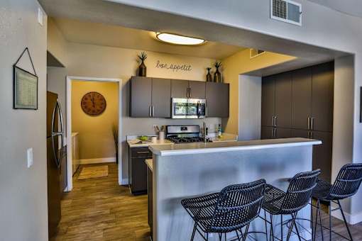 A kitchen with a bar and chairs.