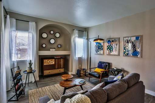 A living room with a grey couch, a wooden coffee table, and a fireplace with a mirror above it.