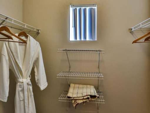 A white robe hanging on a rack in a room.