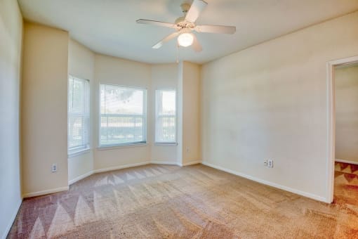 Pet-Friendly Apartments in Beaumont, TX – Breakwater Bay - Living room with plush carpet, windows with coverings and ceiling fan.