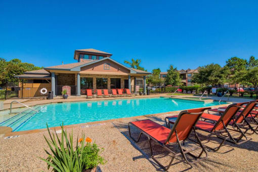 A swimming pool at Lake forest surrounded by beach umbrellas and beach chairs and trees