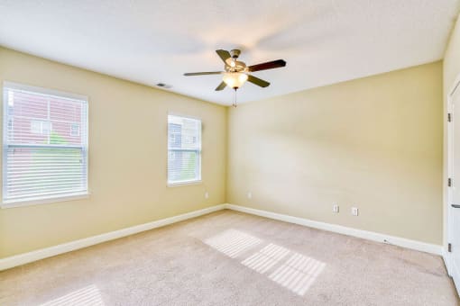 large bedroom with two windows and ceiling fan an light