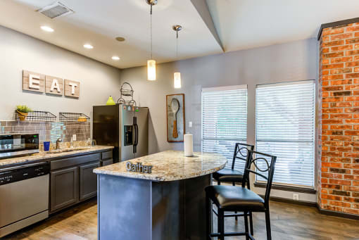 a kitchen with a large island with granite countertops and stainless steel appliances