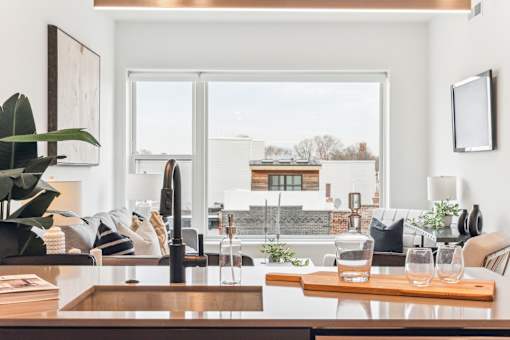 A modern kitchen with a wooden table and a large window overlooking the city.