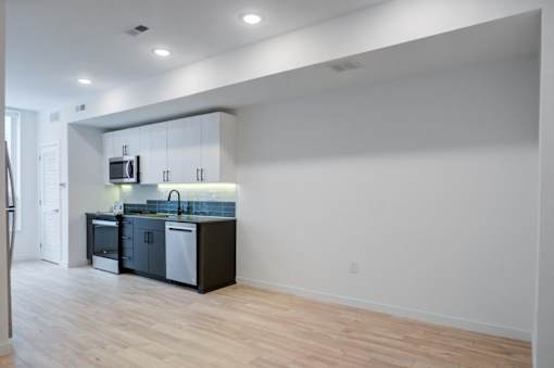 an empty room with a kitchen and a hard wood floor