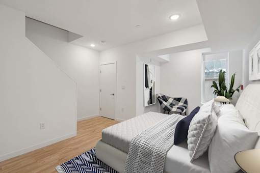 A bedroom with a bed, pillows, and a plant.