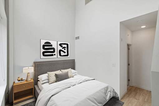 A bedroom with a bed, nightstand, and two framed pictures on the wall.