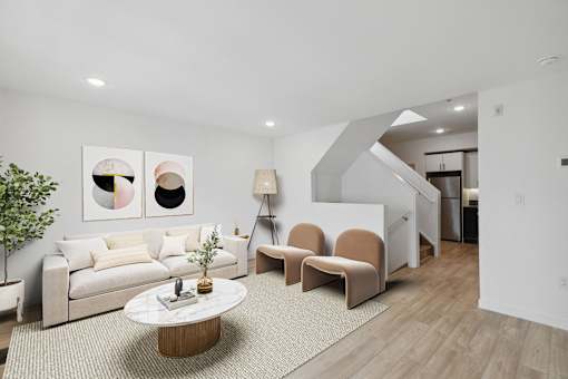 Cozy living area with a beige sofa, chic armchairs, a round marble coffee table, and modern wall art creating a welcoming ambiance.