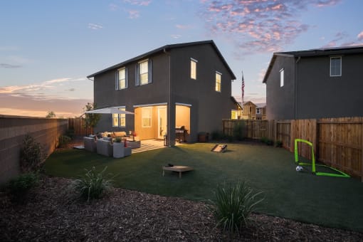 a backyard with a house and a yard with artificial turf and a playground