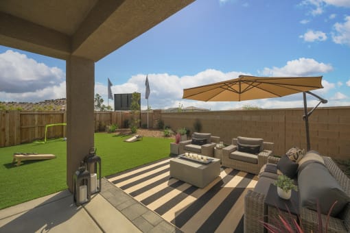 a backyard patio with couches and a table with an umbrella