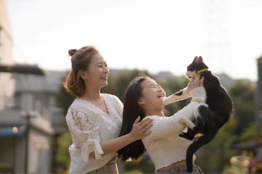 two women playing with a black and white dog