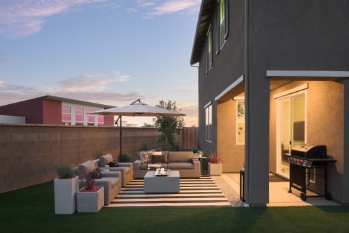 a backyard patio with a grill and a table and chairs