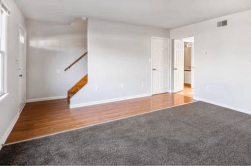 A room with a grey carpet and wooden floors.