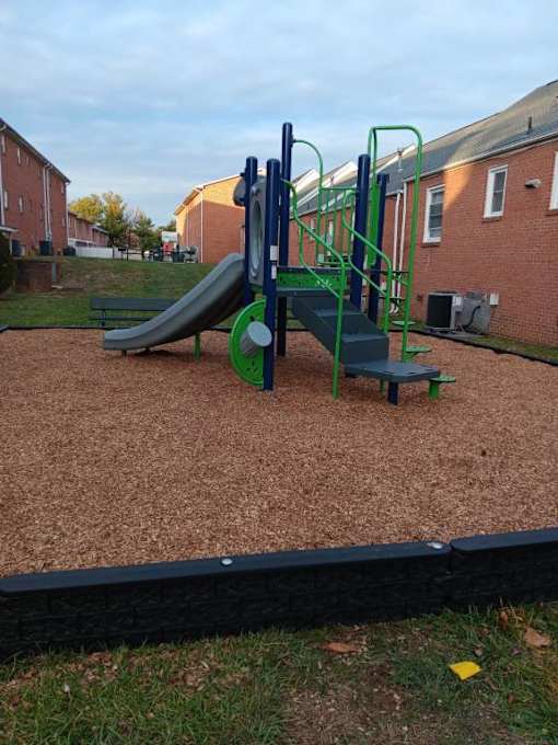 A playground with a green slide and a blue and green climbing frame.
