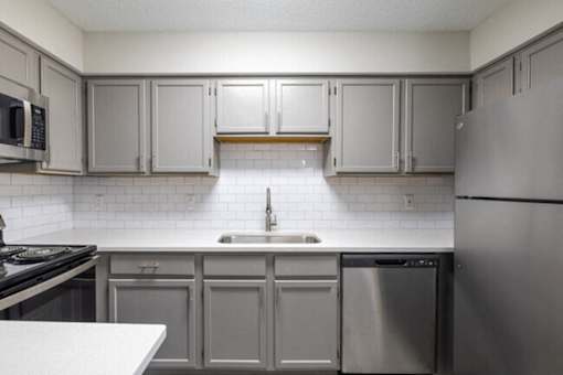 A kitchen with a stainless steel refrigerator, sink, and cabinets.