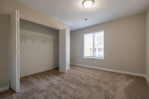 A room with a carpeted floor and a window with blinds.