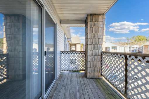A wooden deck with a lattice fence and a glass door leading to a balcony.