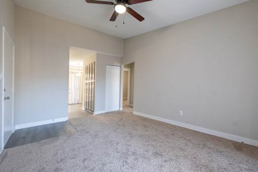 A room with a ceiling fan and carpeted floor.