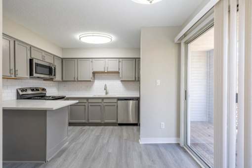 A modern kitchen with a white countertop and stainless steel appliances.