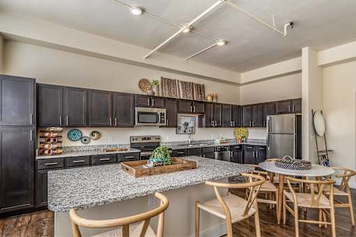 A kitchen with a granite countertop and wooden chairs.