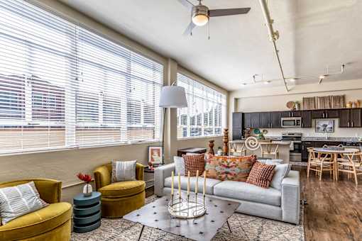 A living room with a yellow armchair, a grey sofa, and a wooden floor.