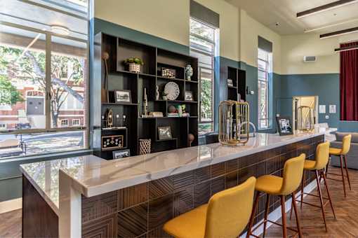 A long bar with yellow chairs and a counter with a clock on it.