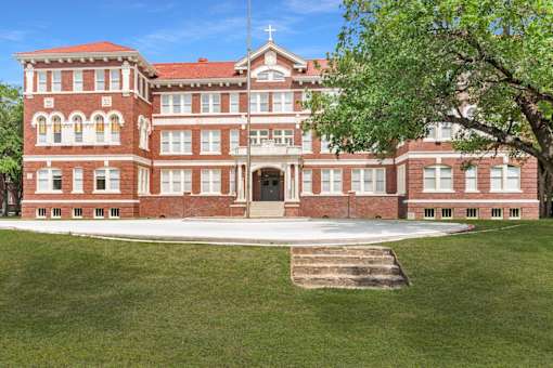 A large red brick building with a cross on top of it.