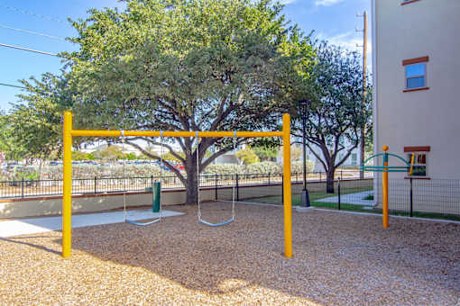 A playground with a swing set and a tree.