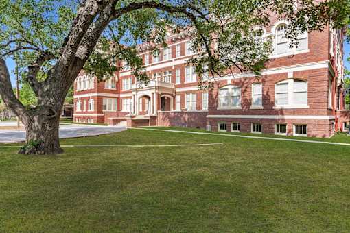 A large red brick building with a tree in front.