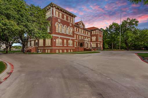 A large red brick building with a parking lot in front.