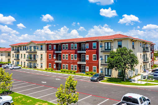 A large apartment complex with a parking lot in front.