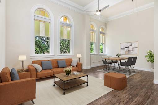 San Antonio, TX, Affordable Apartments With In-Unit Washer And Dryer - The St. John - A Spacious Living Room With Historic Arched Windows, A Tan Sofa, And A Modern Dining Area.