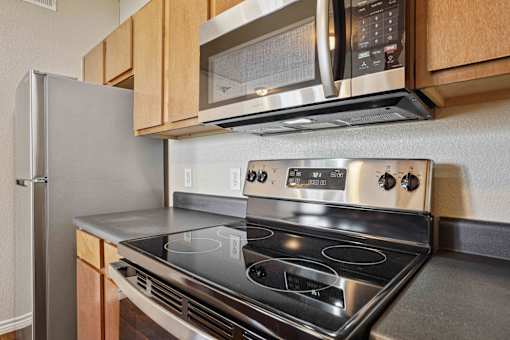 1, 2 & 3-Bedroom Apartments for Rent in Maumelle, AR – Parc at Maumelle – A modern kitchen with a stainless steel stove and microwave above it.